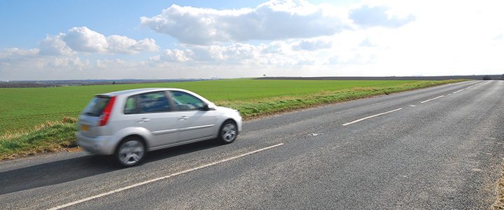 Small car driving along a road in the european countryside