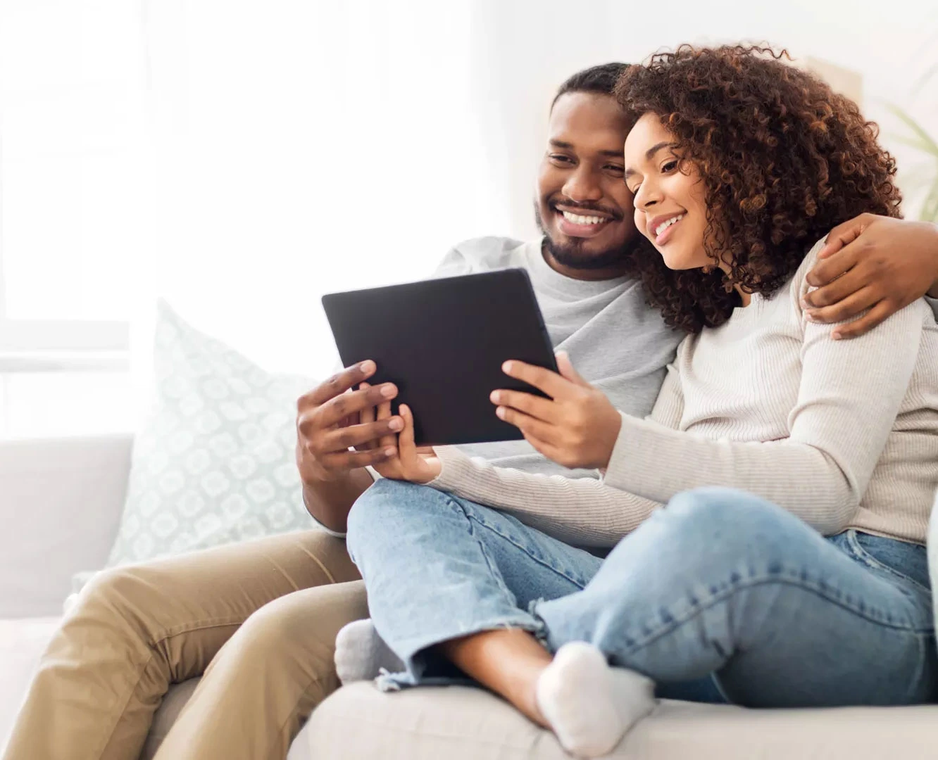 1. A couple sitting together at home, engaged in using a tablet, sharing a moment of connection and collaboration.